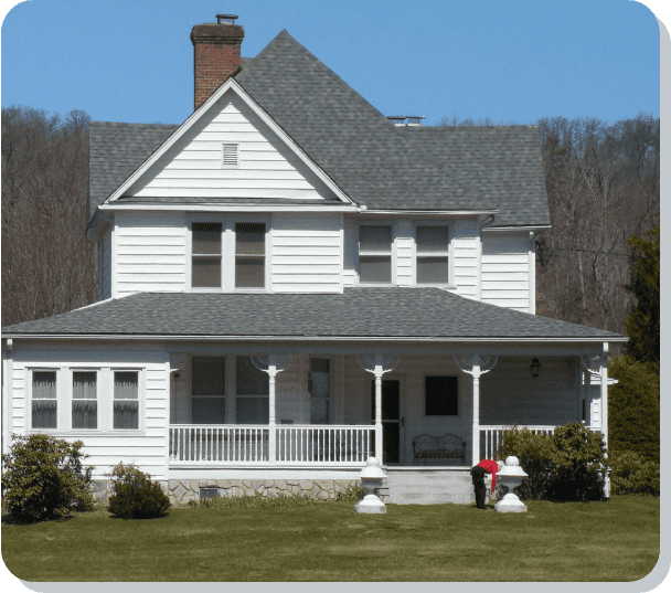 A large white house with a porch and trees in the background.