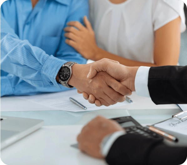 Two people shaking hands over a table.